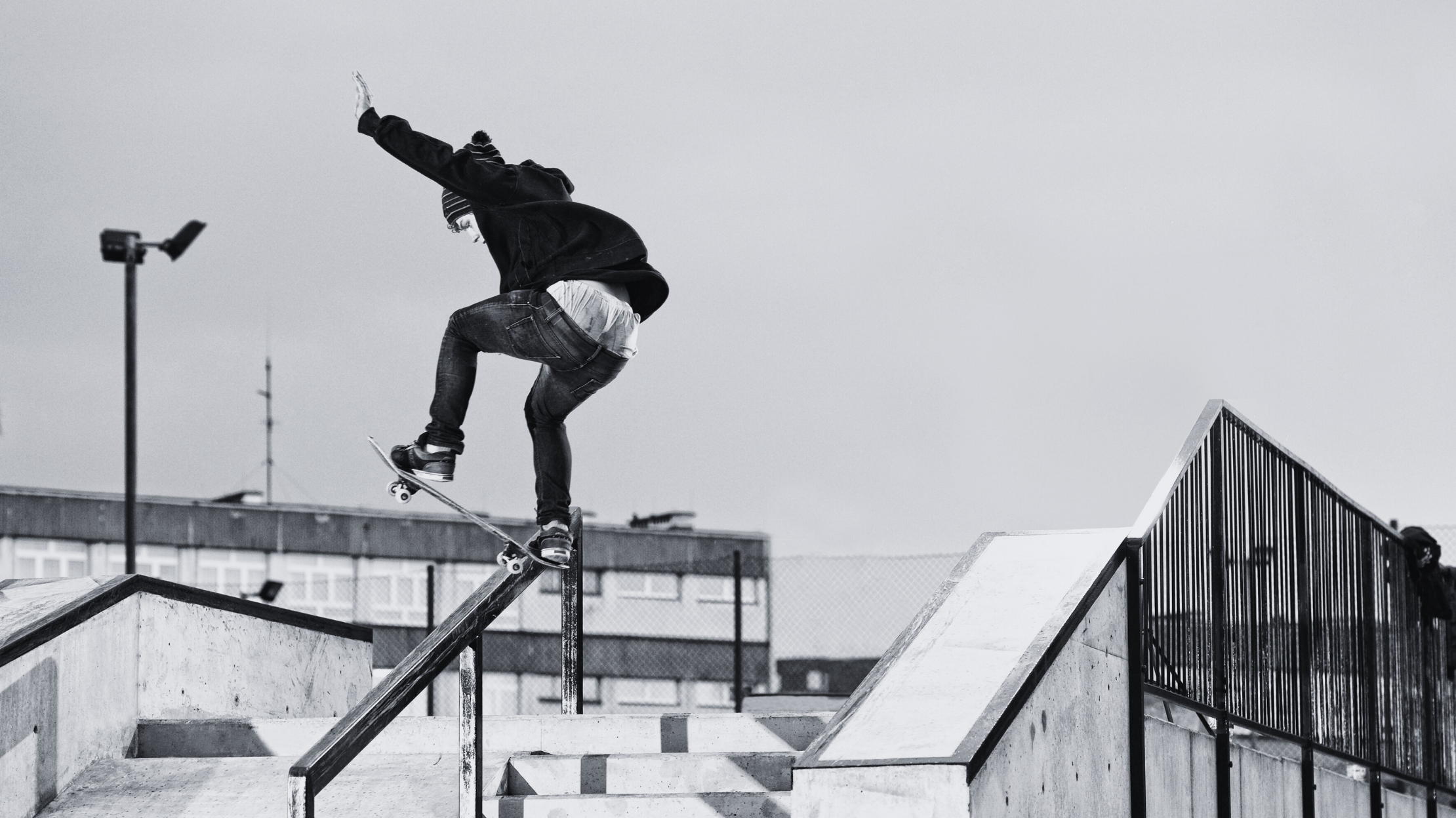 Skateboarder performing a trick on a railing with a cityscape background